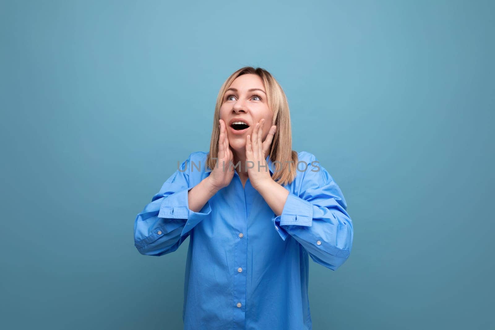 shocked young woman in casual look grabbing her head on blue background.