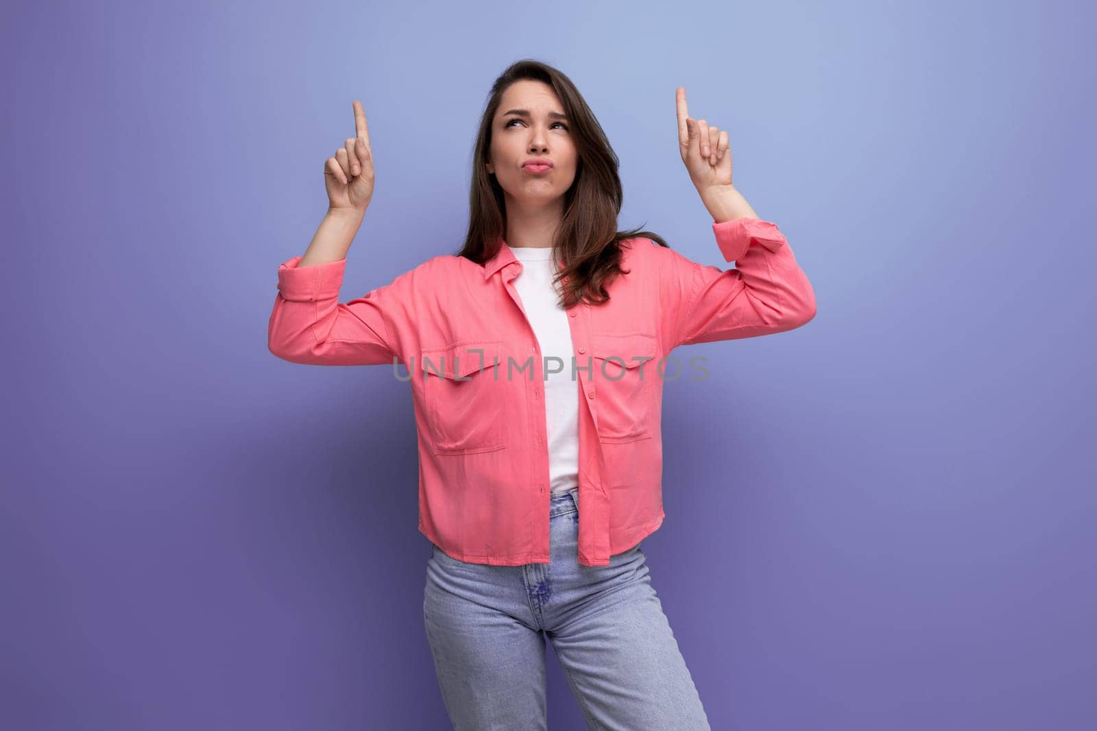 focused black haired lady in casual style pointing thumb up at mockup space on studio background.