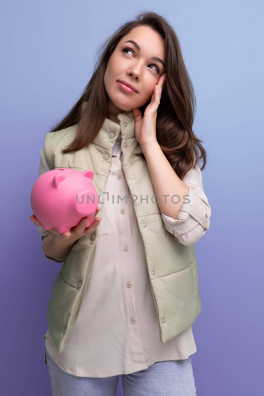 young brunette woman decides where to invest her savings from the piggy bank.