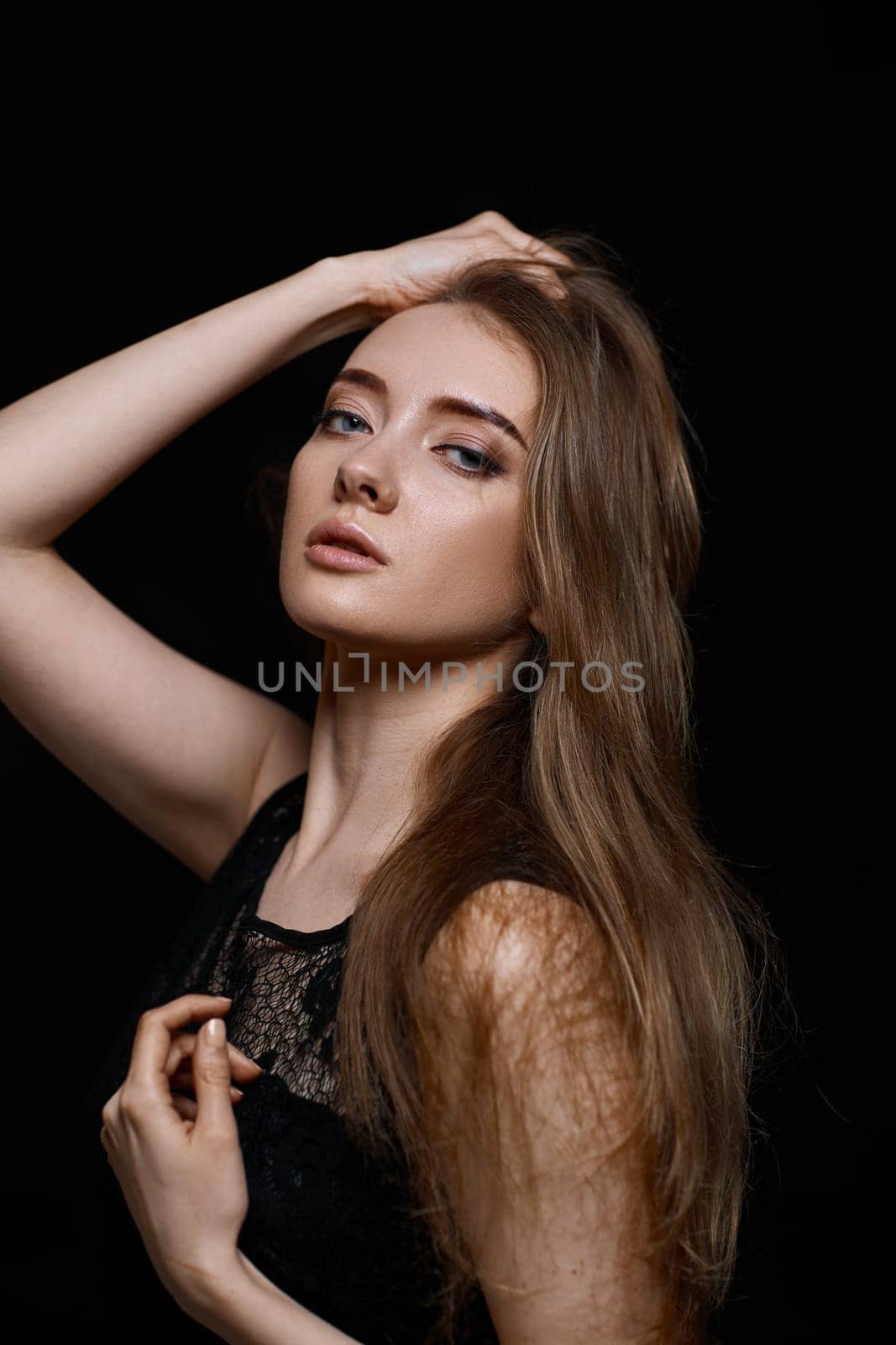 gorgeous brunette woman with long hair in black dress on black background