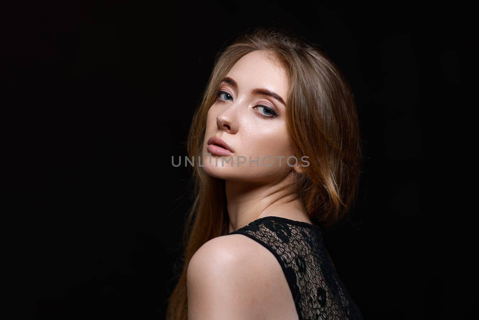 gorgeous brunette woman with long hair in black dress on black background. copy space