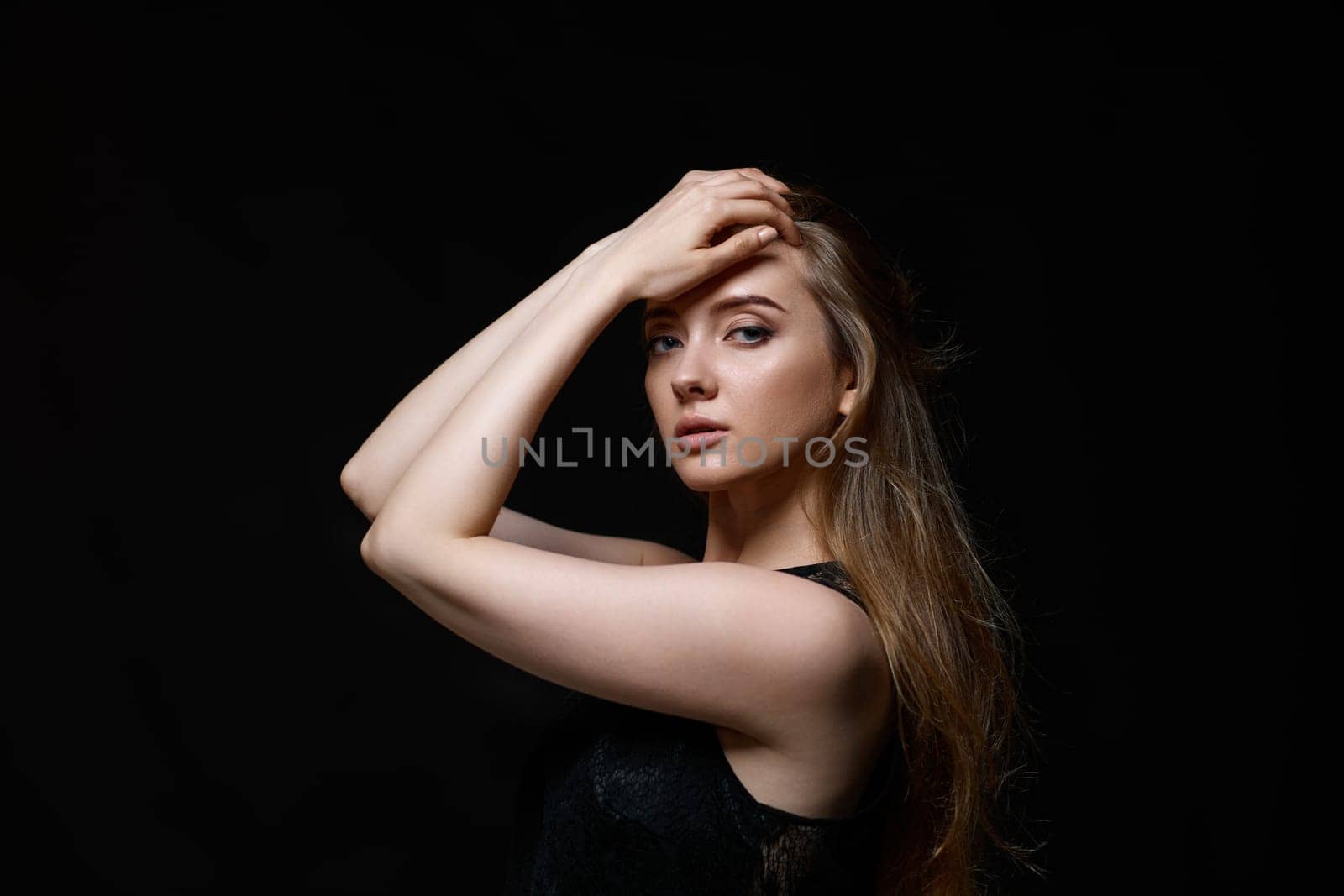 gorgeous brunette woman with long hair in black dress on black background. copy space
