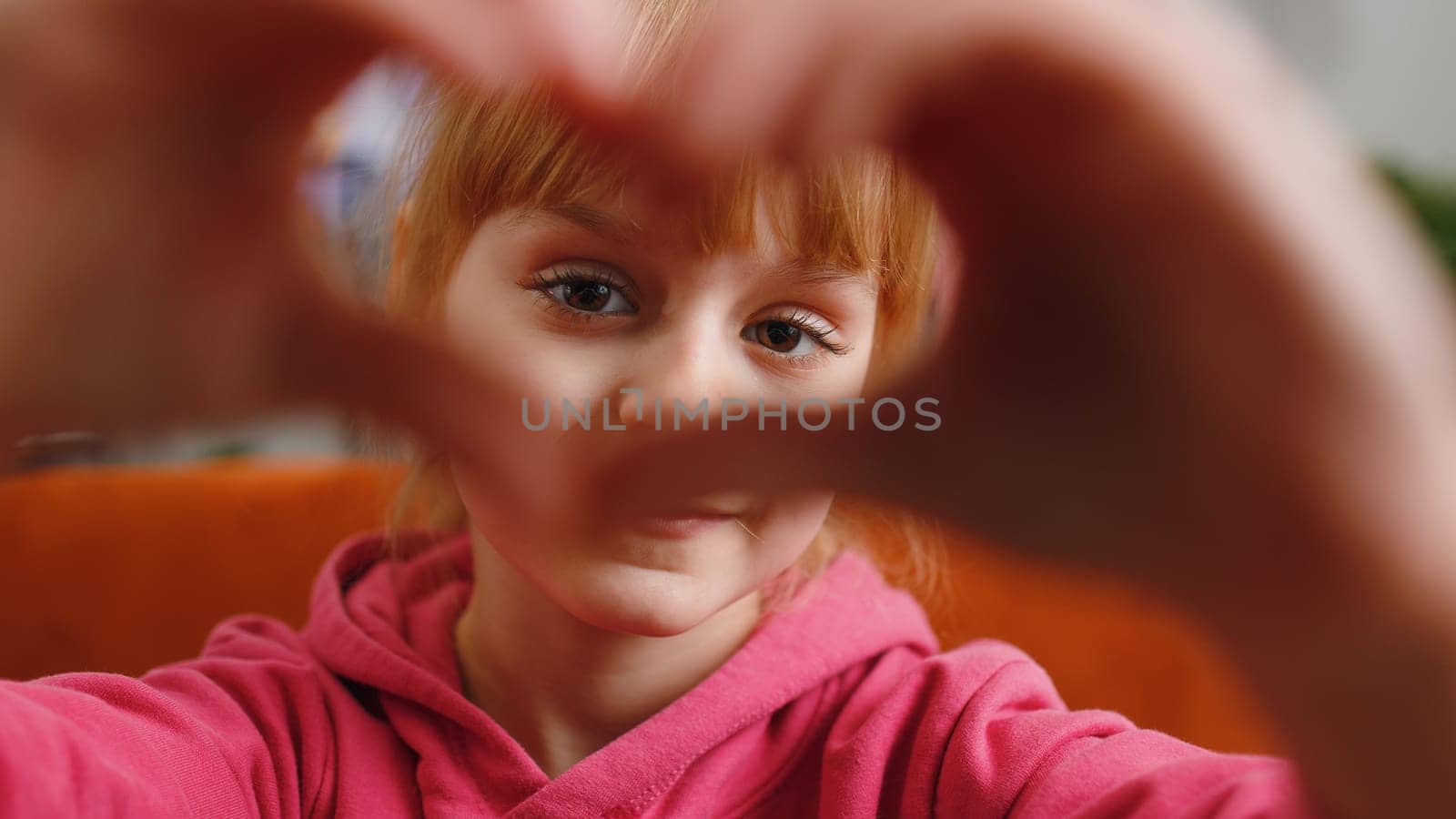 I love you. Child kid girl makes symbol of love, showing heart sign to camera, express romantic feelings, express sincere positive feelings. Charity, gratitude, donation. Female teen toddler at home