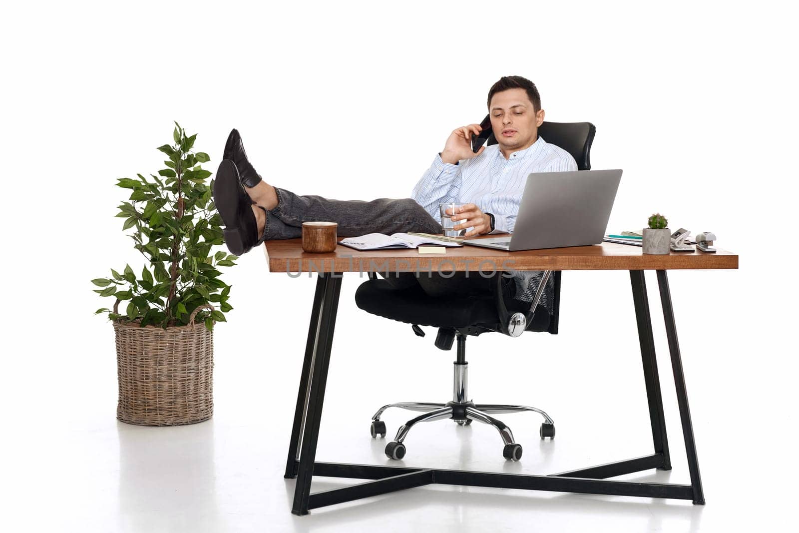 Successful freelancer man working with laptop and having phone conversation with client