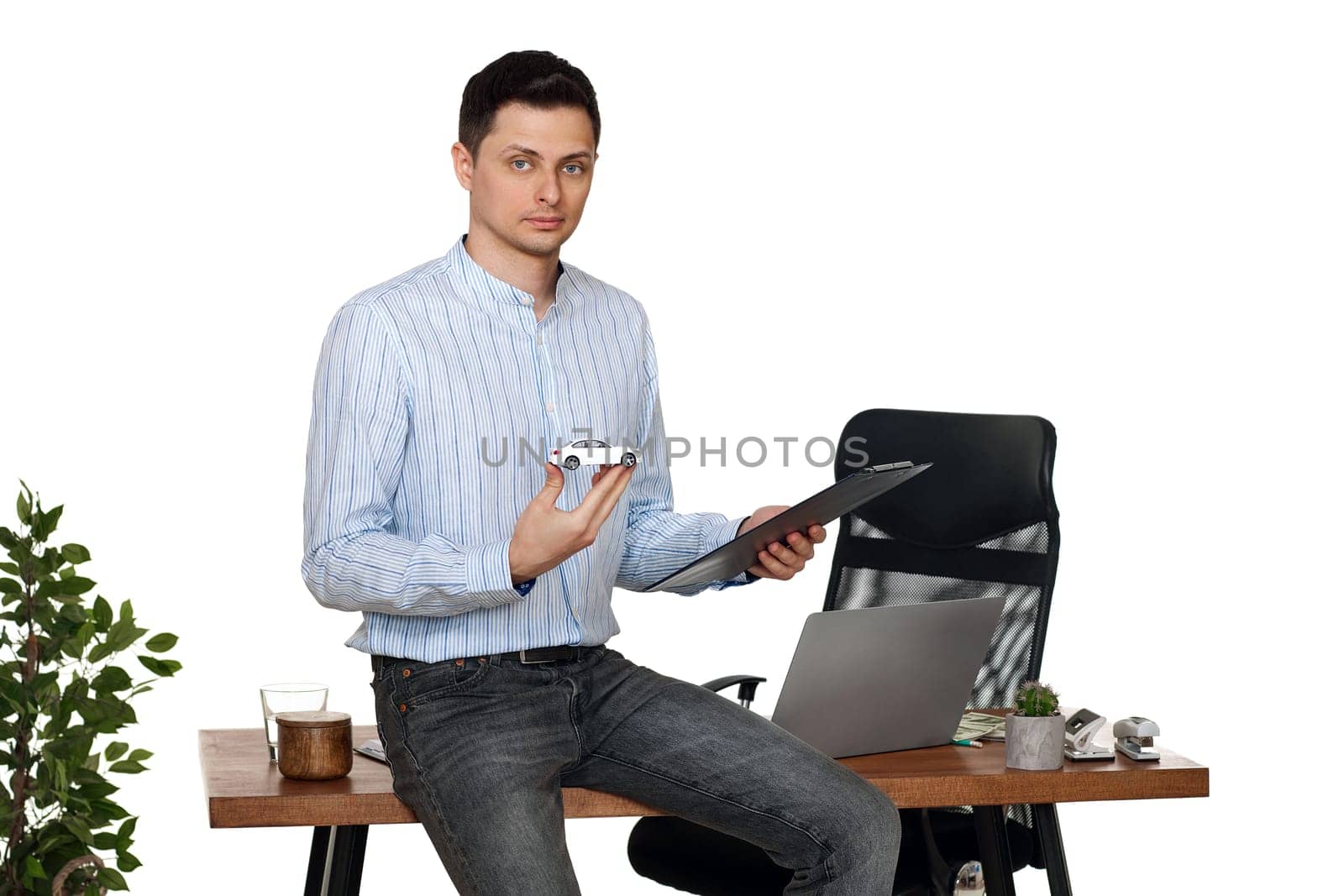 Successful caucasian businessman holding a toy car while standing at desk. Car dealerships offer car . Car insurance
