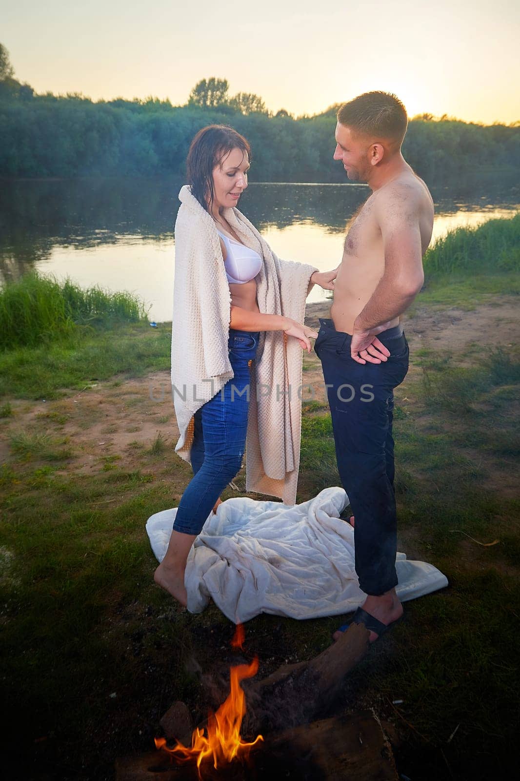 Happy Couple Outdoor relaxin and having fun on nature in the park in summer evening with smog and fog. Family or lovers have date and rest outdoors. Girl takes off jeans from a man or a guy by keleny