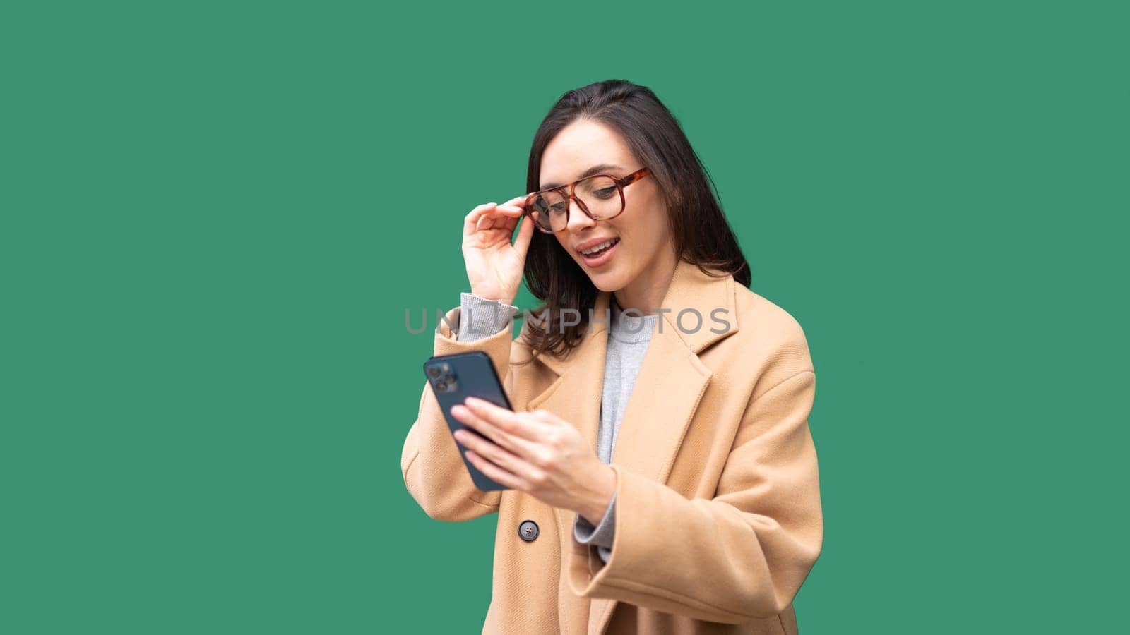 Happy, excited woman with smartphone for text message isolated on green, notification and social media news. Deal, winner and celebration for offer, giveaway and surprise