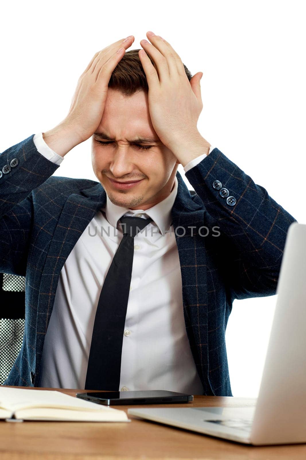 young businessman using laptop, sitting on chair at desk, having problems thinking about troubles in office