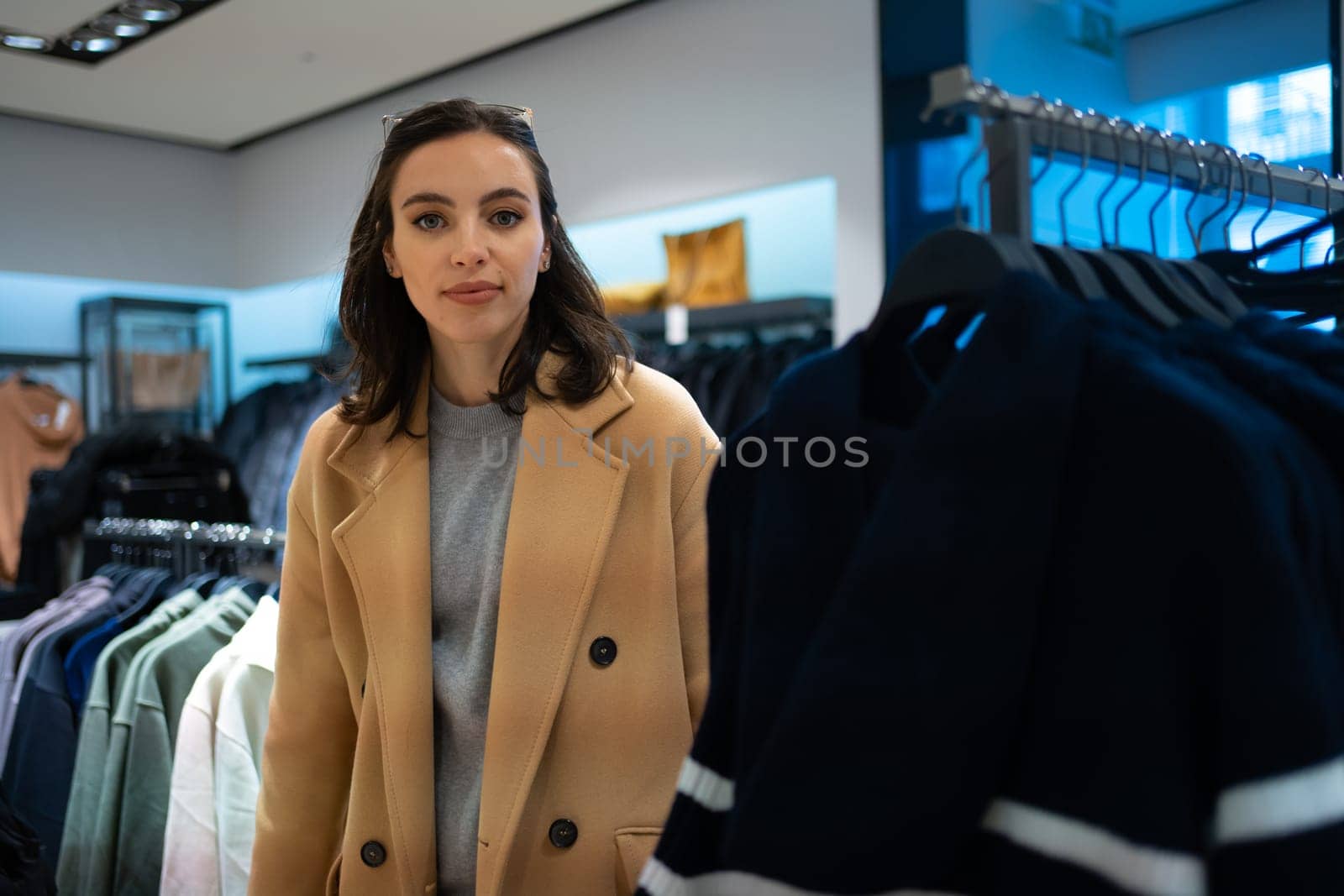 Woman choose what to buy in clothes store by andreonegin