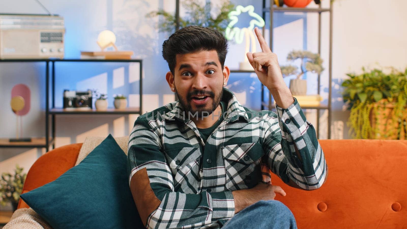 Eureka. Thoughtful clever inspired indian man make positive gesture raises finger came up with creative plan feels excited with good idea, inspiration motivation. Hindu guy at home in living room
