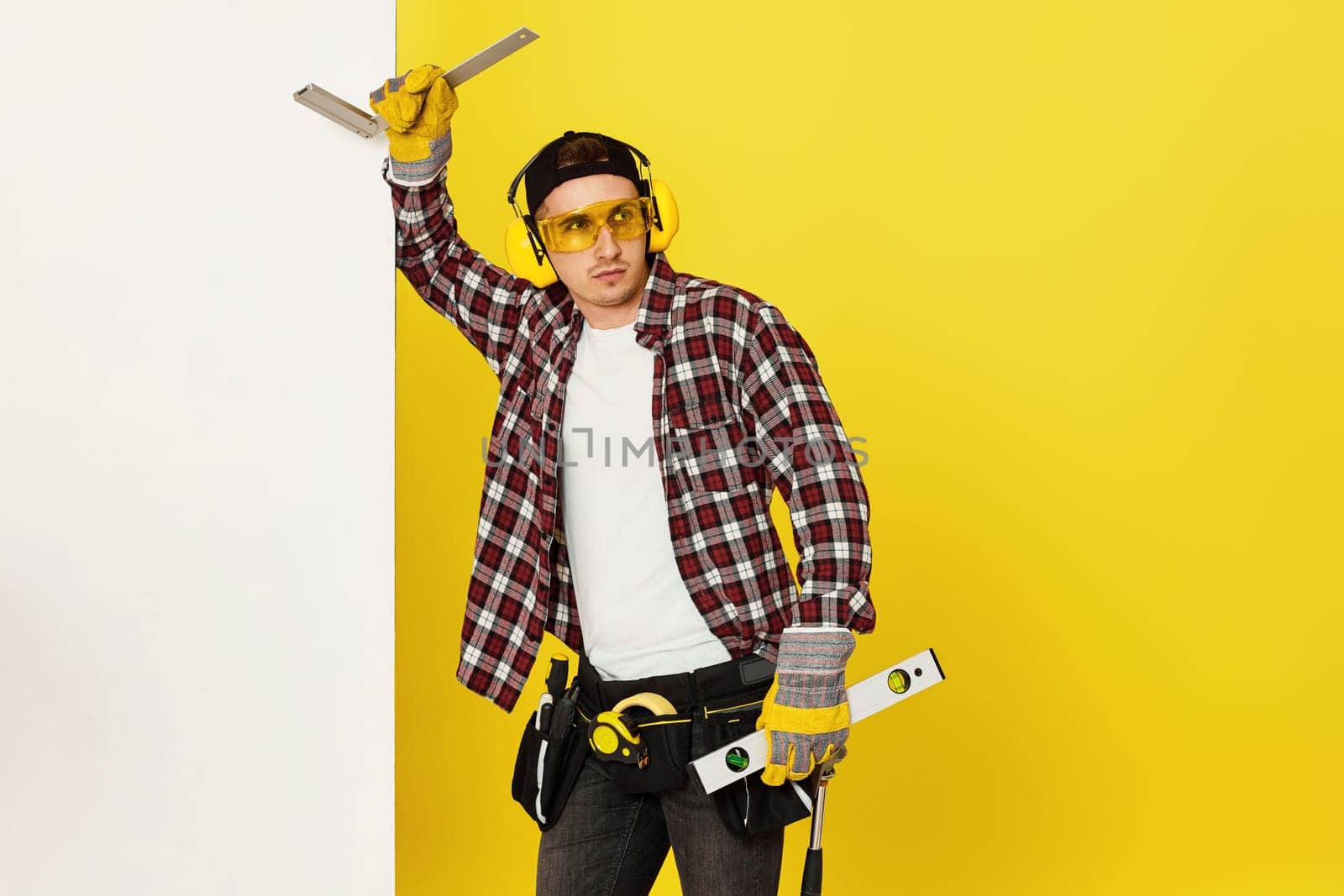 Worker man or builder in construction helmet near white banner on yellow background. building carpentry profession