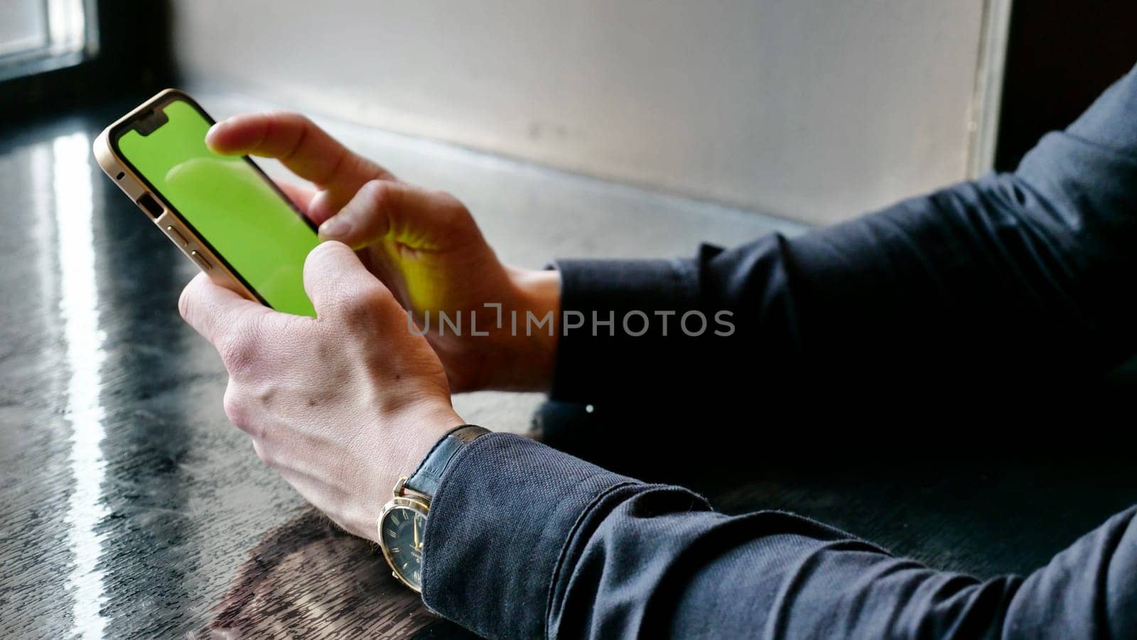 Close-up device smartphone with green screen in men's hands. A businessman scrolls the phone with chroma key in the office.