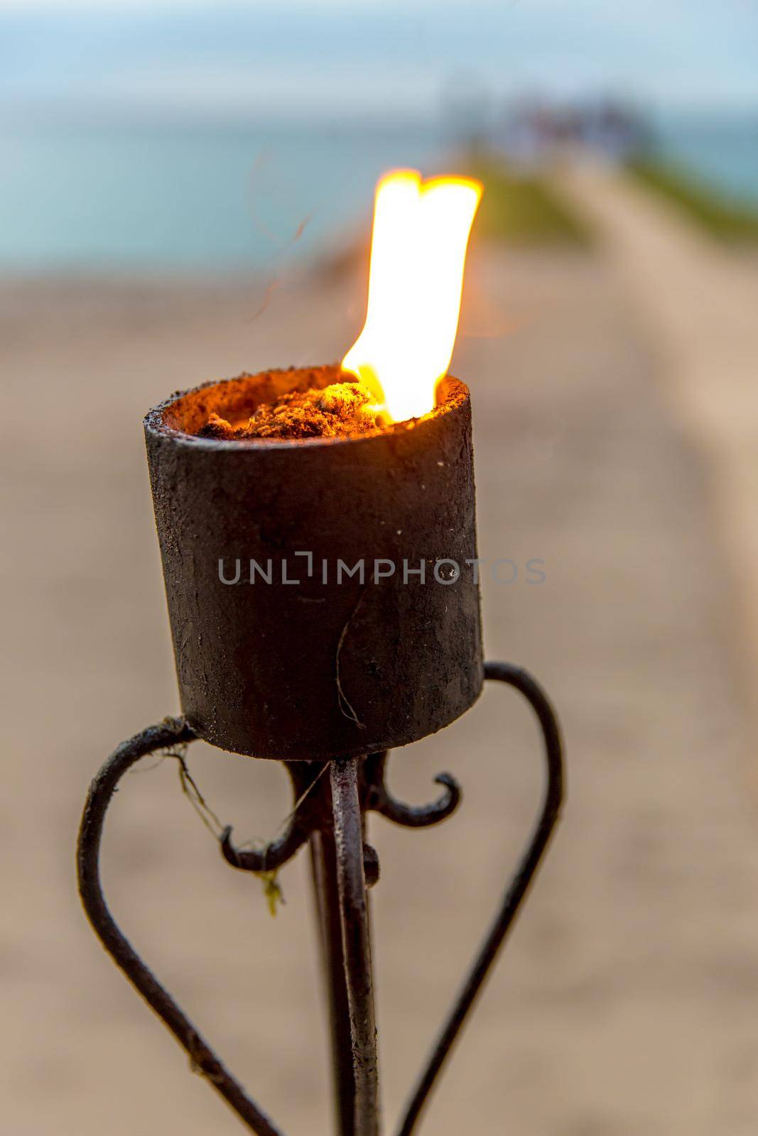 Oceanfront wedding at sunset with lit torches. Focus is on the torch.