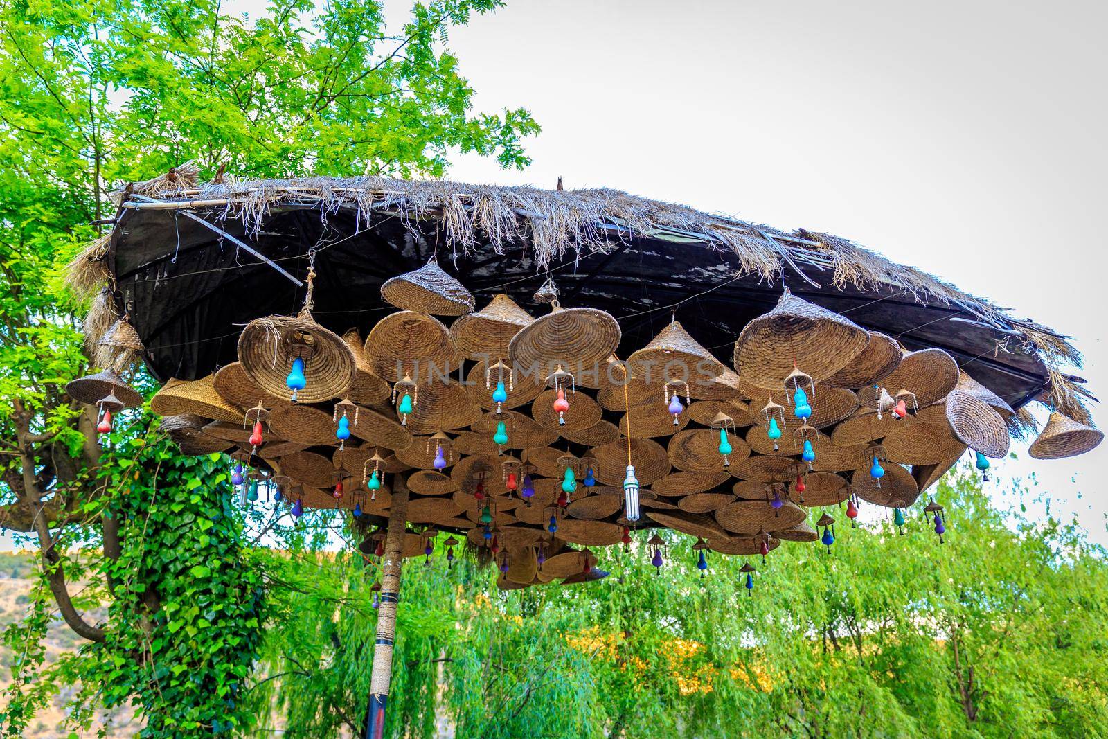 Huge umbrella of strawhats made into wind bells, in Guanyin Gorge Park, Li Jiang, Yunnan Province, China.