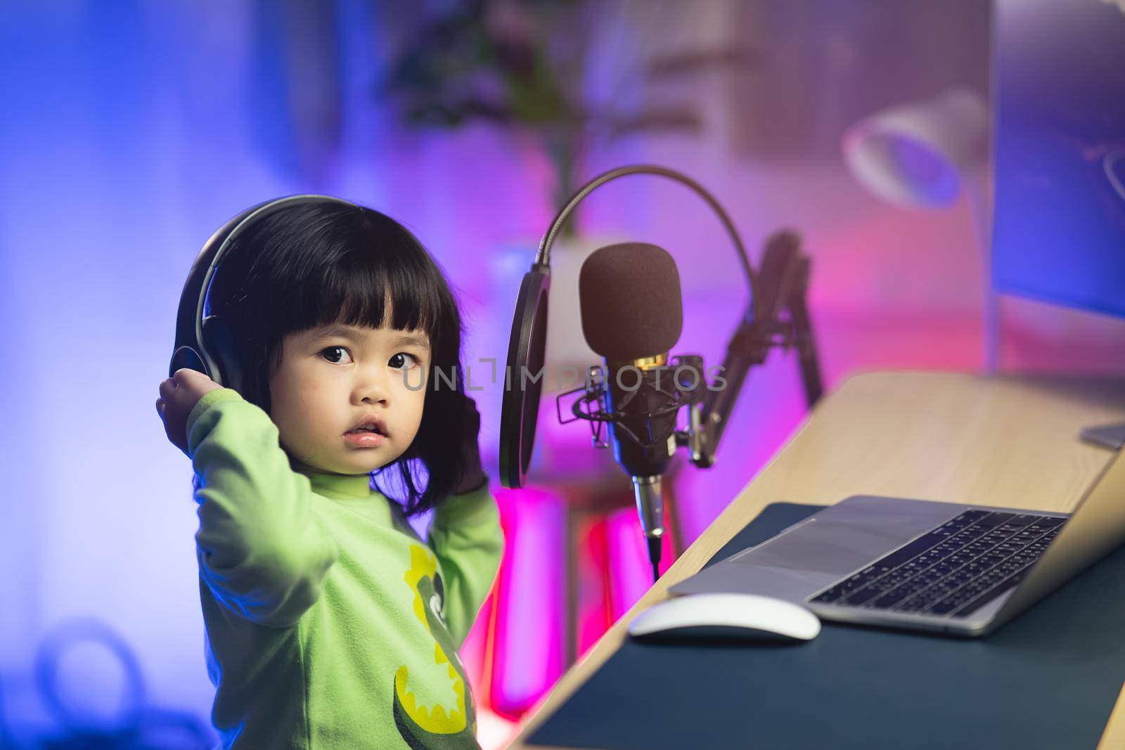 cute baby girl singing with headphone recording new song with microphone in the home recording studio by Wmpix
