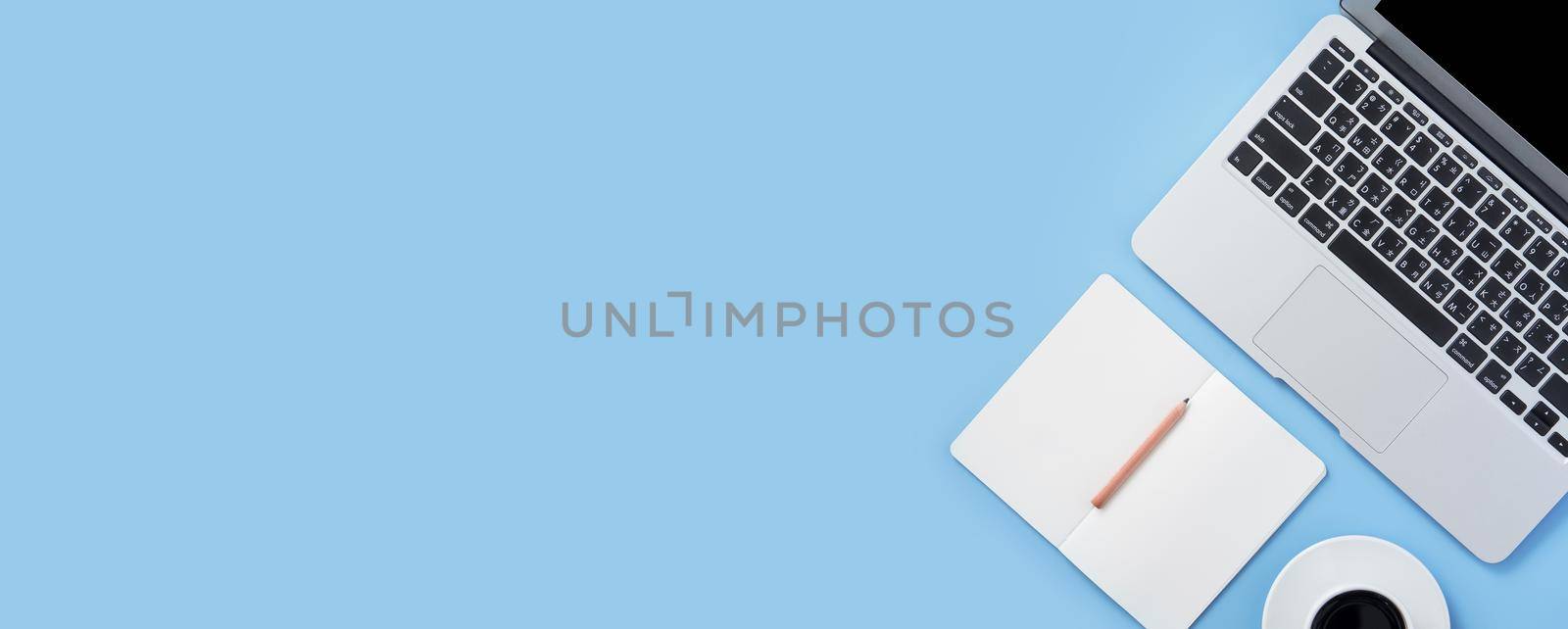 Girl write on open white book or accounting on a minimal clean light blue desk with laptop and accessories, copy space, flat lay, top view, mock up