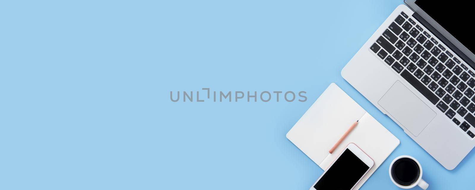 Girl write on open white book or accounting on a minimal clean light blue desk with laptop and accessories, copy space, flat lay, top view, mock up by ROMIXIMAGE