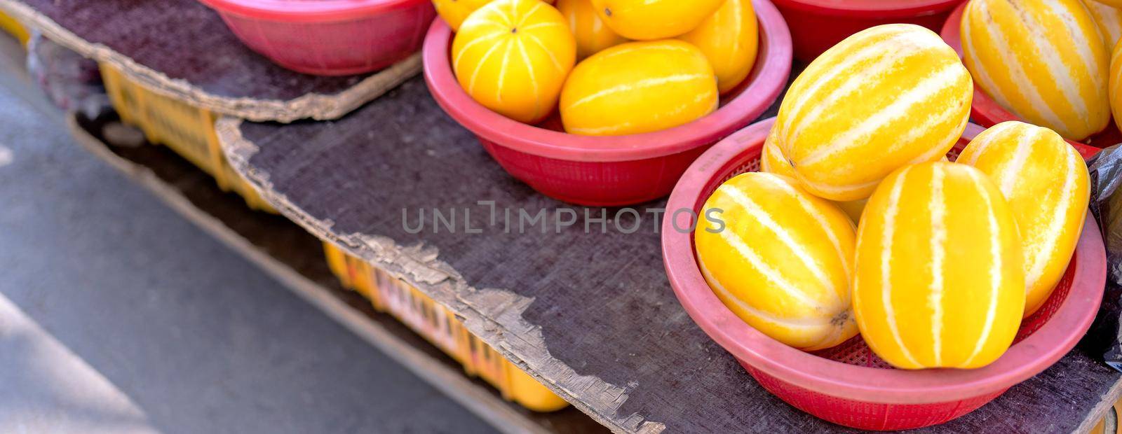Delicious korean stripe yellow melon fruit food in red plastic basket at tradition market afternoon, Seoul, South Korea, harvest concept, close up.