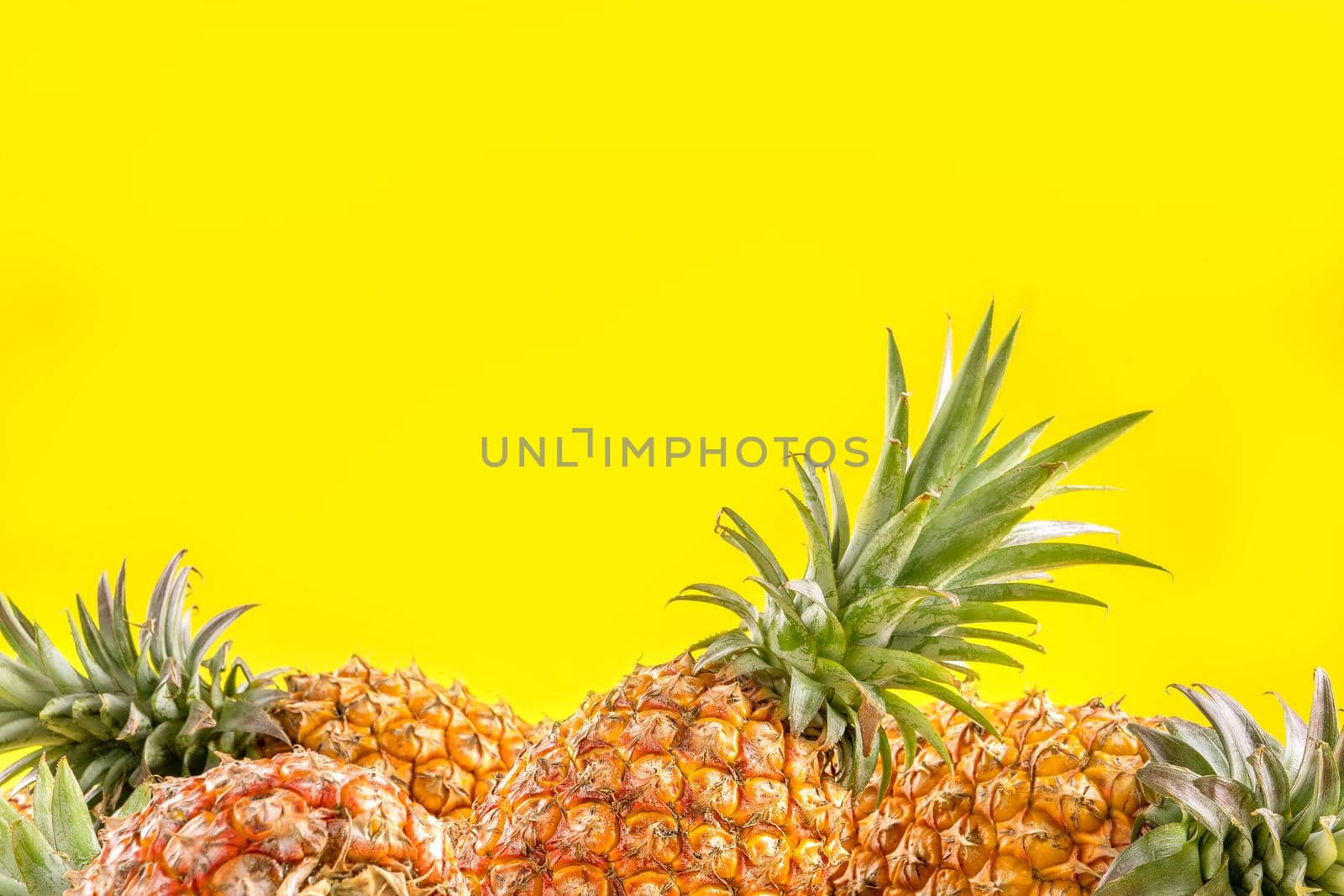 Beautiful fresh pineapple isolated on bright yellow background, summer seasonal fruit design idea pattern concept, copy space, close up by ROMIXIMAGE