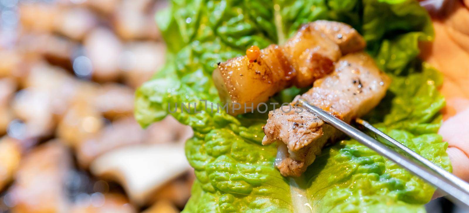 Pan-fried cooked black pork meal in Korea restaurant, fresh delicious korean food cuisine on iron plate with lettuce, close up, copy space, lifestyle