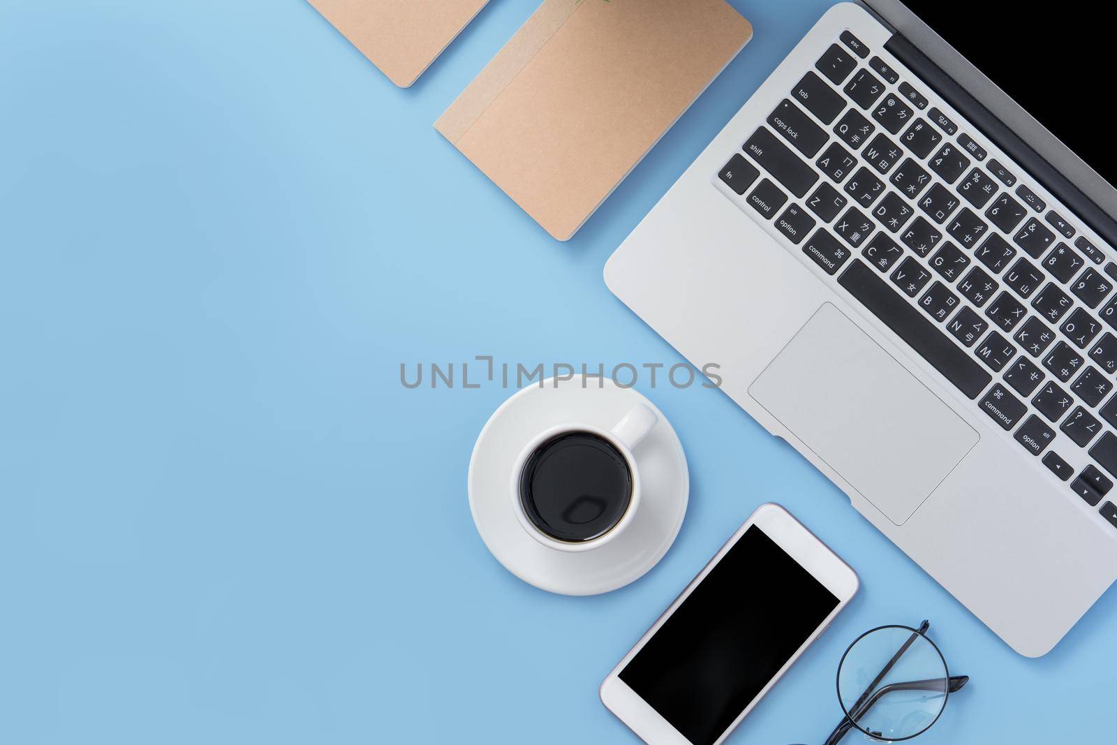 Business concept. Clean bright light blue office table desk, minimal style with laptop coffee and smart phone, copy space, top view, flat lay, mockup by ROMIXIMAGE