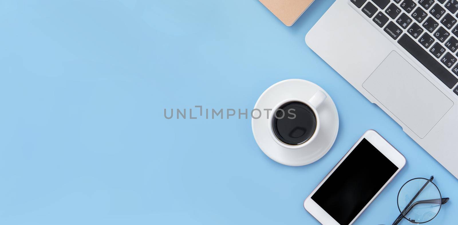 Business concept. Clean bright light blue office table desk, minimal style with laptop coffee and smart phone, copy space, top view, flat lay, mockup