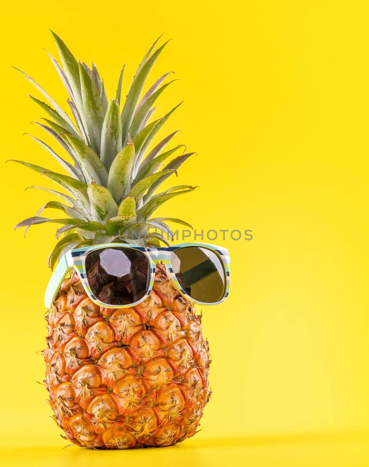 Creative pineapple looking up with sunglasses and shell isolated on yellow background, summer vacation beach idea design pattern, copy space close up by ROMIXIMAGE