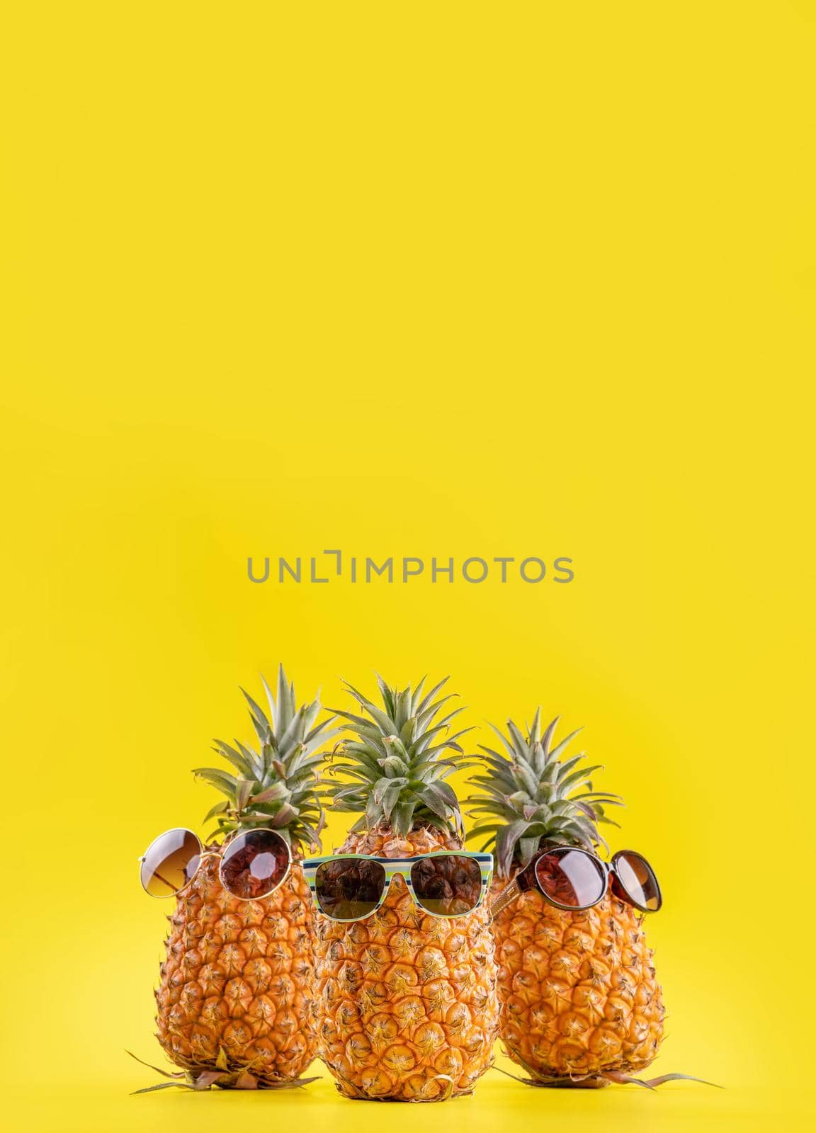 Creative pineapple looking up with sunglasses and shell isolated on yellow background, summer vacation beach idea design pattern, copy space close up by ROMIXIMAGE