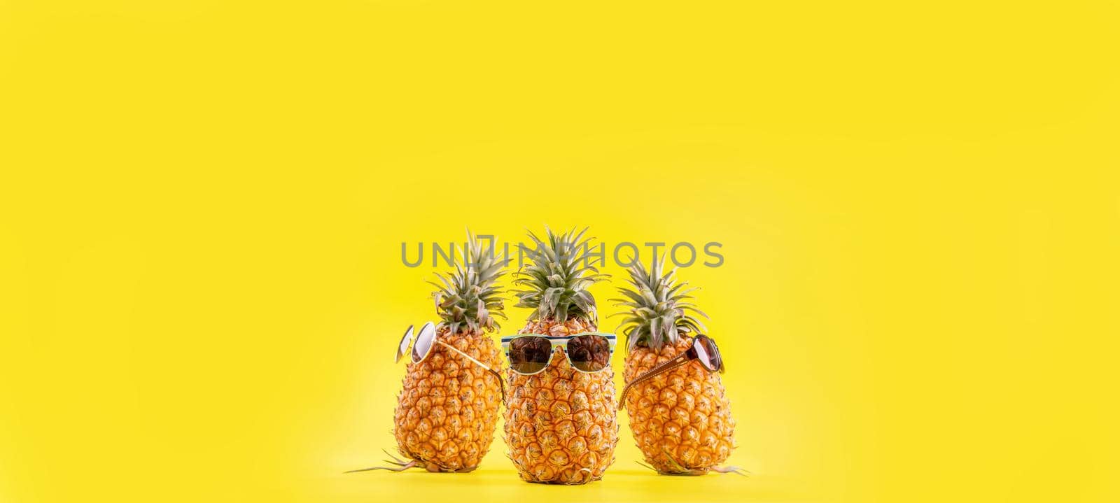 Creative pineapple looking up with sunglasses and shell isolated on yellow background, summer vacation beach idea design pattern, copy space close up