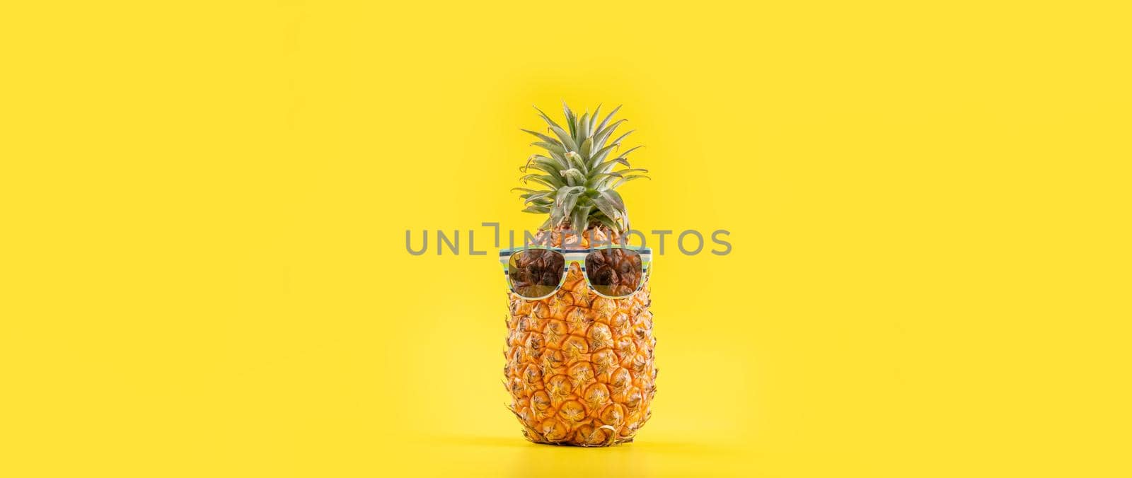 Creative pineapples with sunglasses isolated on yellow background, summer vacation beach idea design pattern, copy space, close up, blank for text by ROMIXIMAGE
