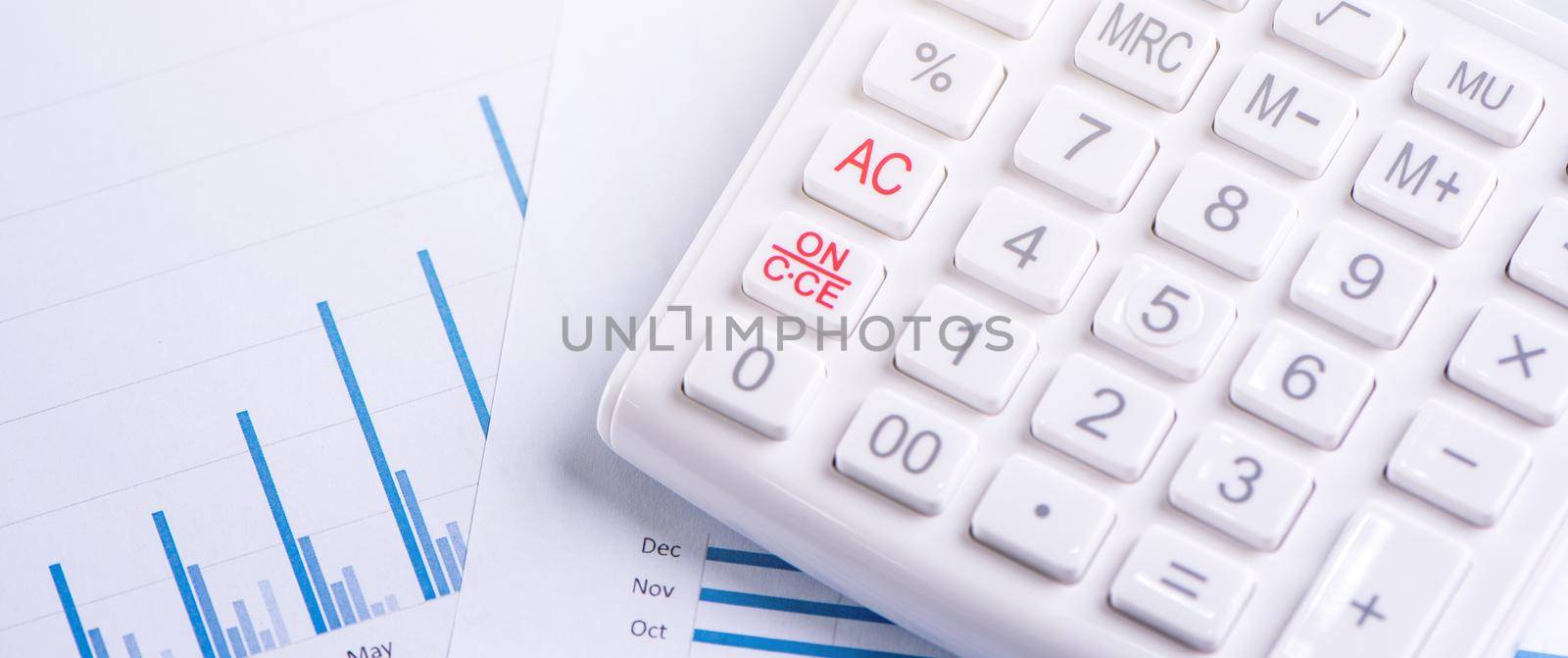 White calculator and report with chart and graph, concept of annual financial profit overview, banking and investment, copy space, macro, close up