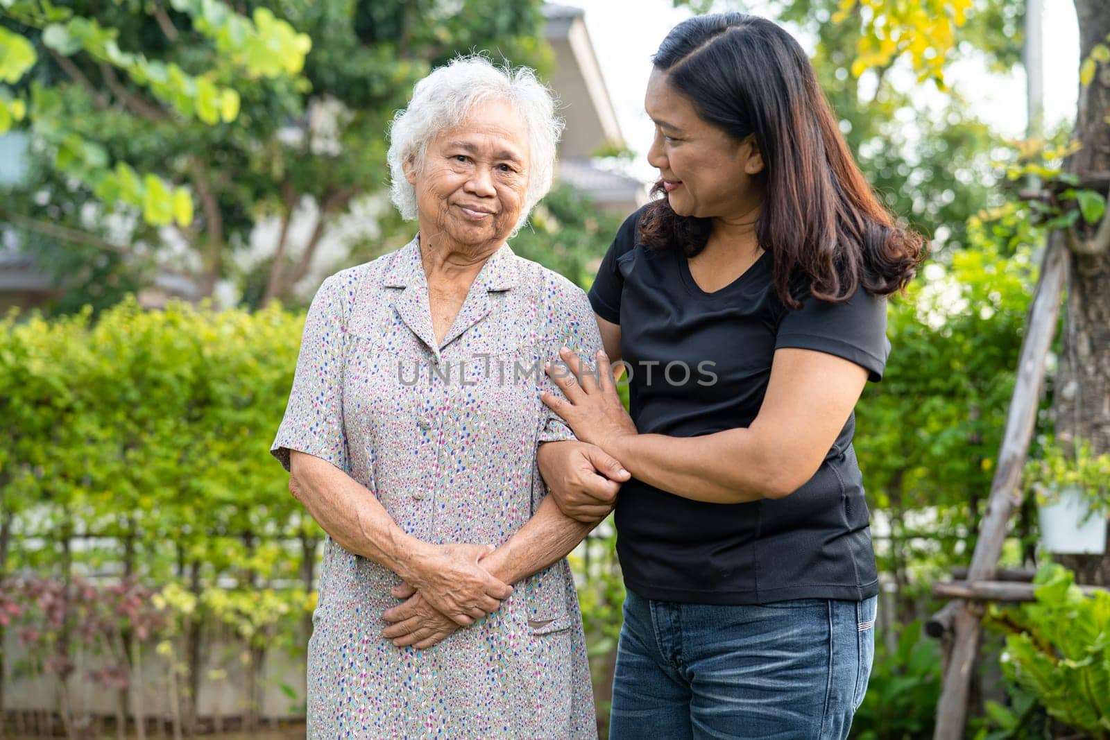 Doctor caregiver help and care Asian senior woman patient walking in park at hospital. by pamai