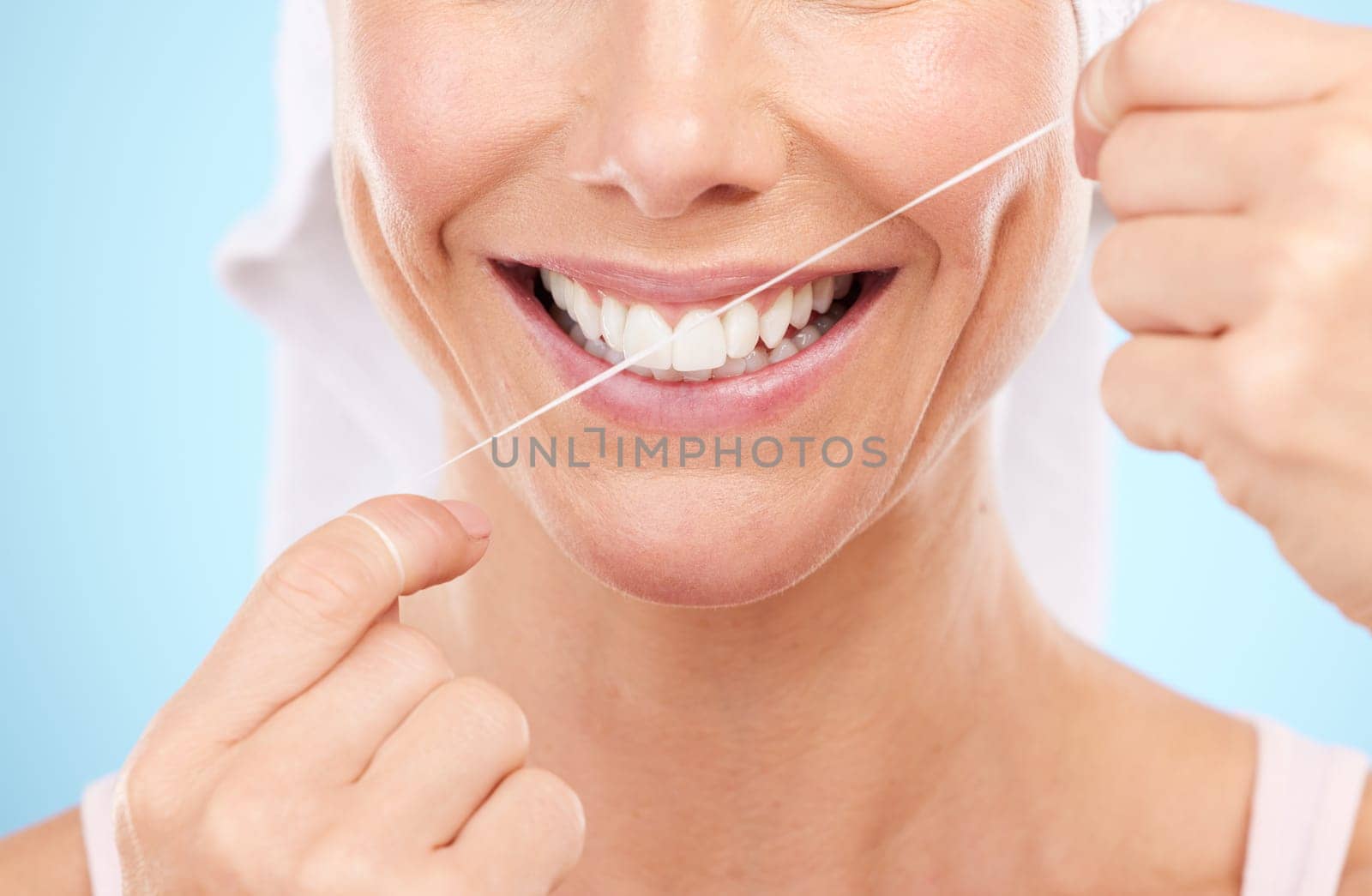 Floss, dental wellness and mouth of woman in studio for beauty, healthy face and happiness on blue background. Closeup model, tooth flossing and cleaning for facial smile, mint breath and happy teeth.