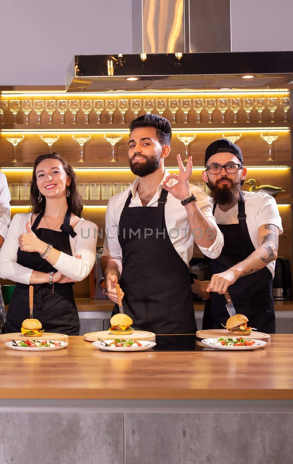 Happy chef and his colleague standing at kitchen and looking at camera - food and restaurant