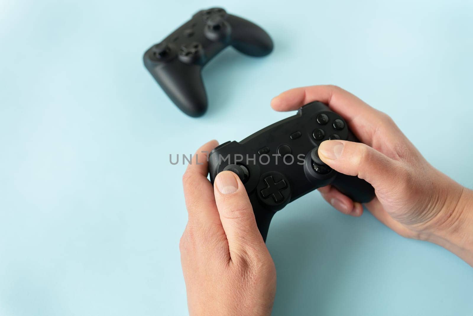 Isolated hands on a blue background that hold a joystick. Gamer, game, recreation, competition