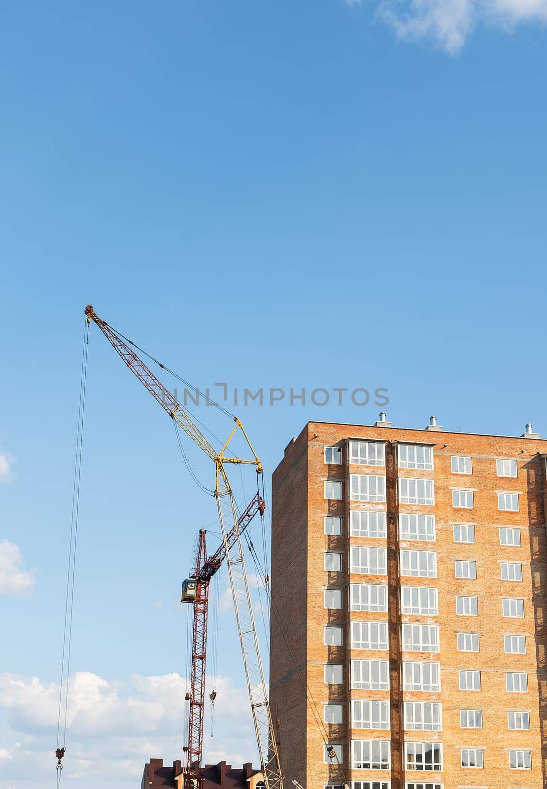 Construction of a new apartment building, against the blue sky, a high-rise construction crane. Vertical photo. by sfinks