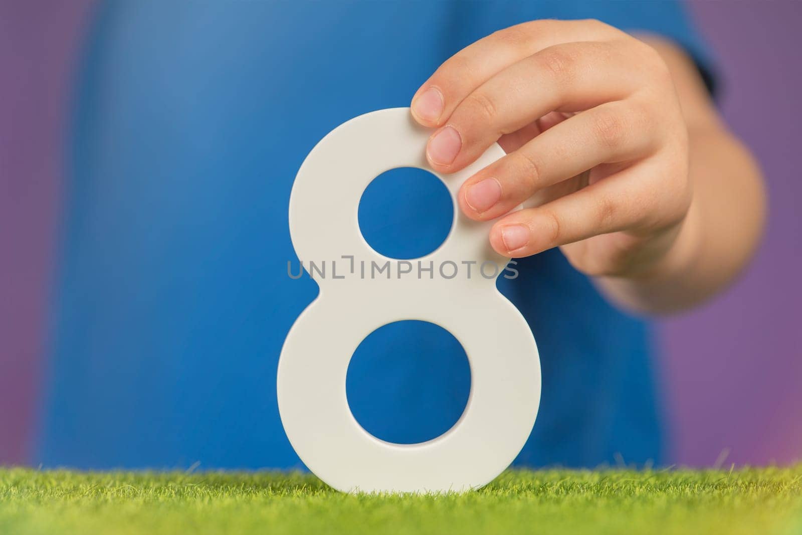 Number 8 in hand. A hand holds a white number eight on a purple background, eight percent per annum. The concept of international women's day on March 8. Advertising banner or greeting card