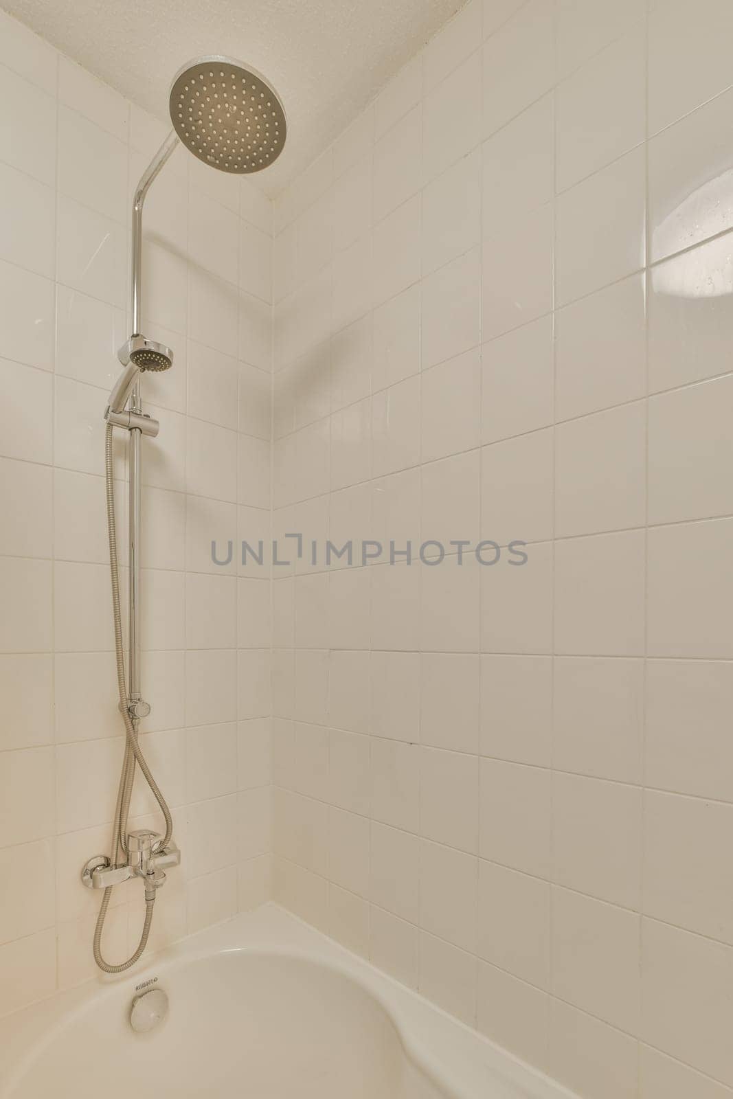 a bathtub with the shower head in it's position and hands on the edge of the tubpipe