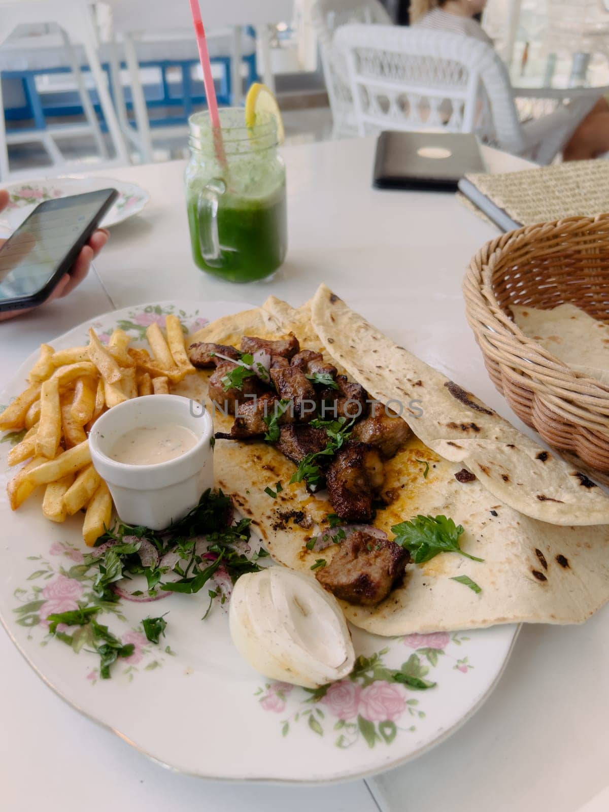 Shish kebab with parsley in pita bread on a plate next to the sauce. High quality photo