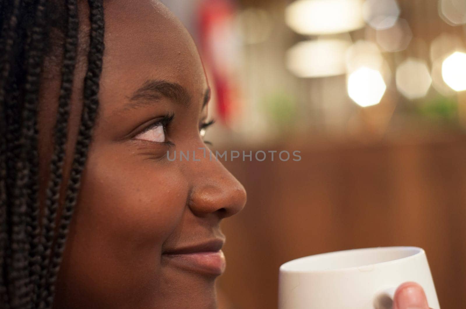 closeup of young afro man with a cup of coffee looking relaxing in a coffee shop. High quality photo