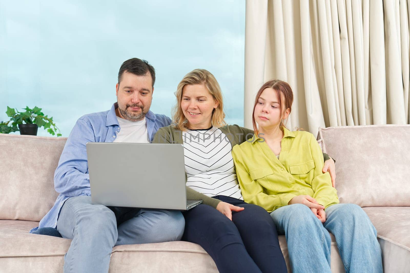 Happy family with kids sit on sofa in living room have fun and watch video using laptop together by PhotoTime