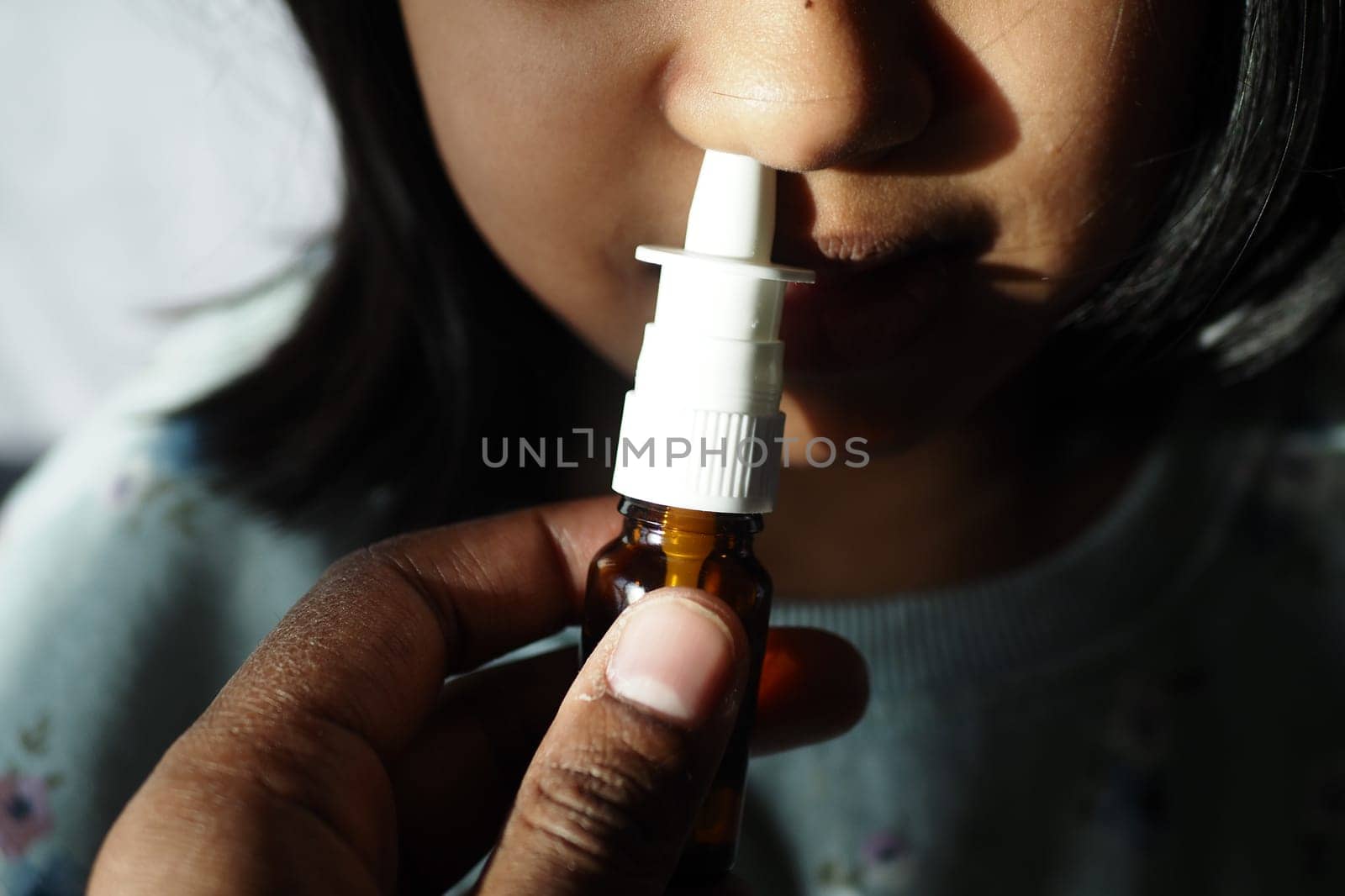 close up of sick child using nasal medicine spray.