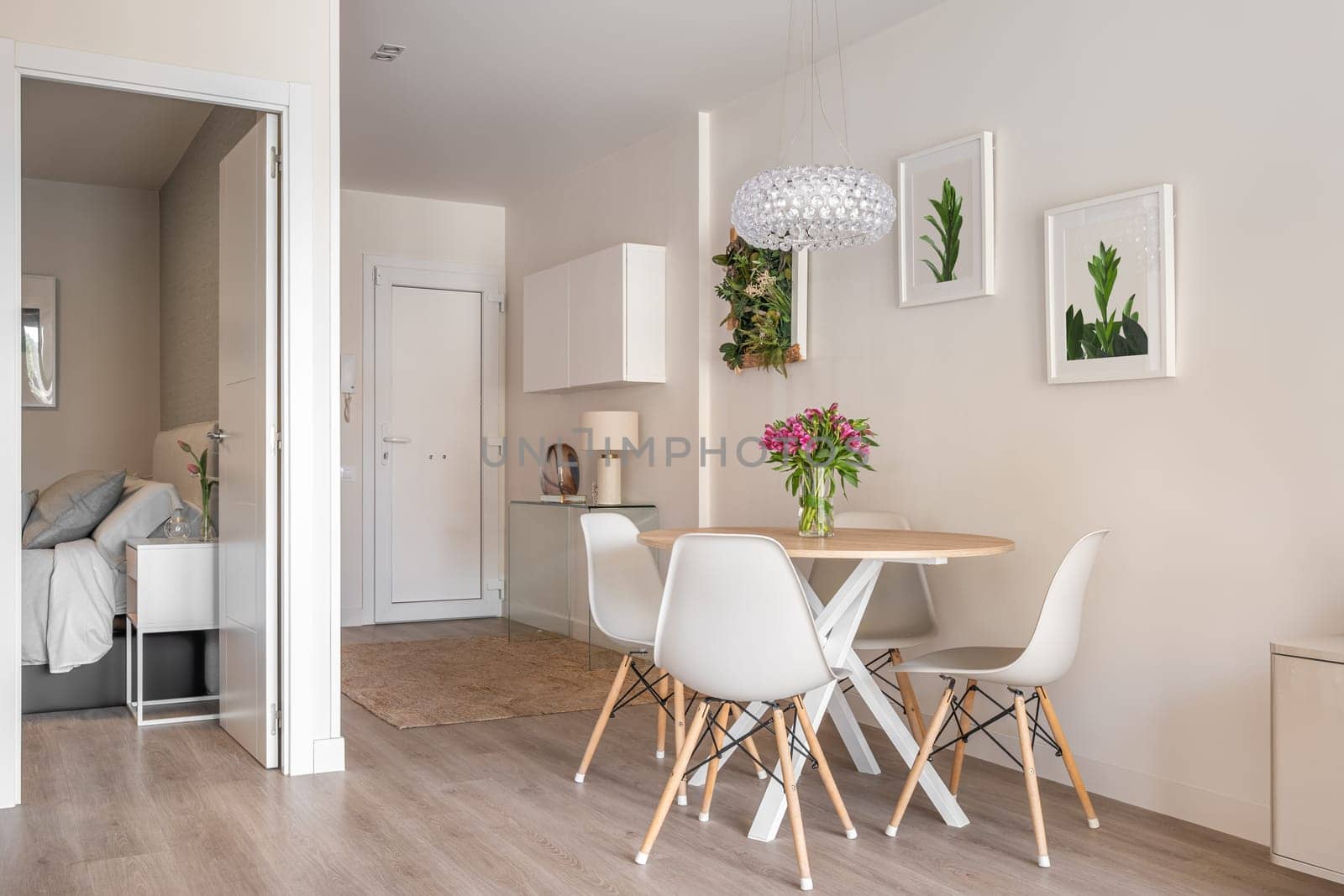 Stylish interior in a compact apartment with a spacious combined living room with table, chairs and decorative accessories overlooking the open bedroom. Cozy city apartment.
