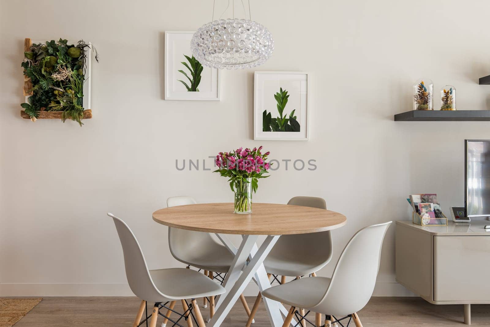Cozy stylish living room with a round dining table, chairs and TV with decorative accessories on the shelves. The concept of a modern city apartment in a mortgage by apavlin