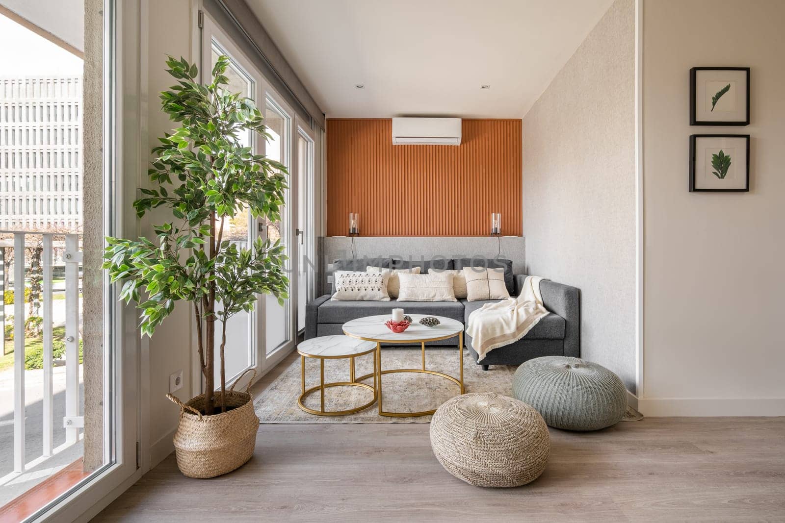 Stylish seating area with a terracotta color wall with a sofa and pouffes near the panoramic windows in the living room. The concept of a modern Scandinavian interior by apavlin