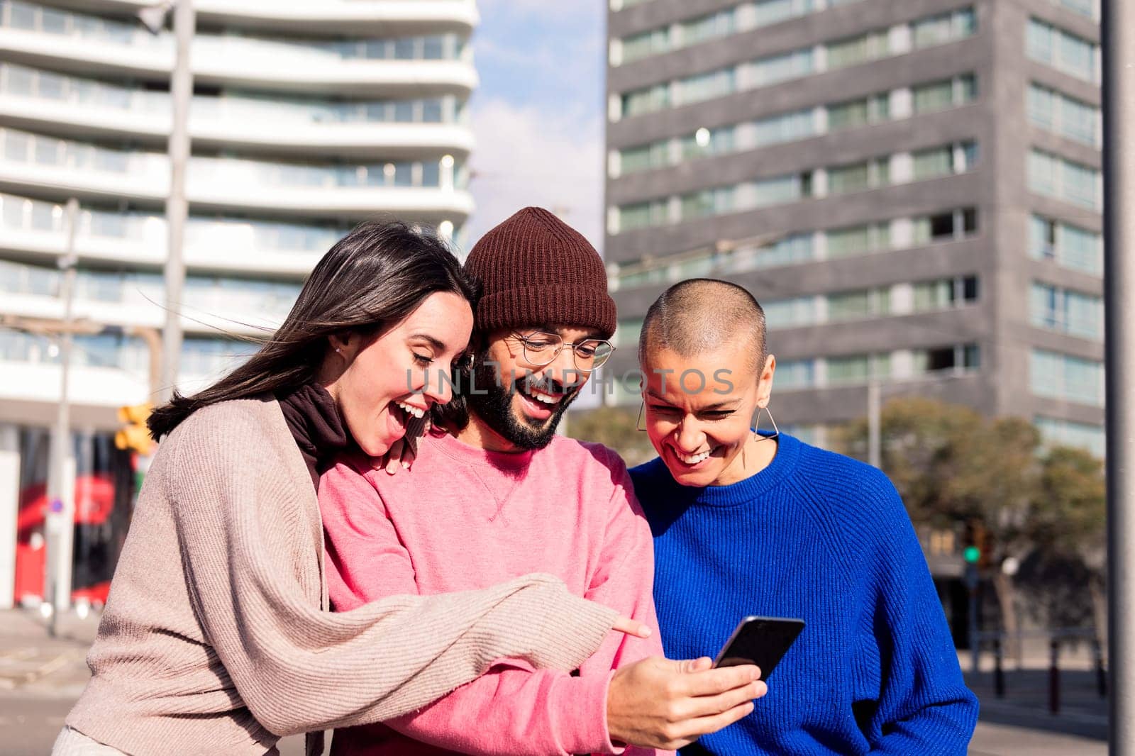 three young friends enjoying social media together with a phone at city, concept of fun with technology and urban lifestyle, copy space for text