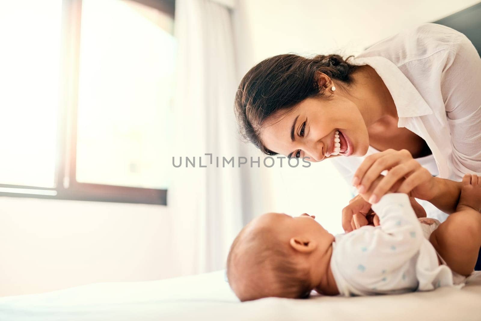 Happy, love and a mother with her baby in the bedroom of their home together for playful bonding. Family, children and a young mama spending time with her newborn infant on the bed for fun or joy by YuriArcurs