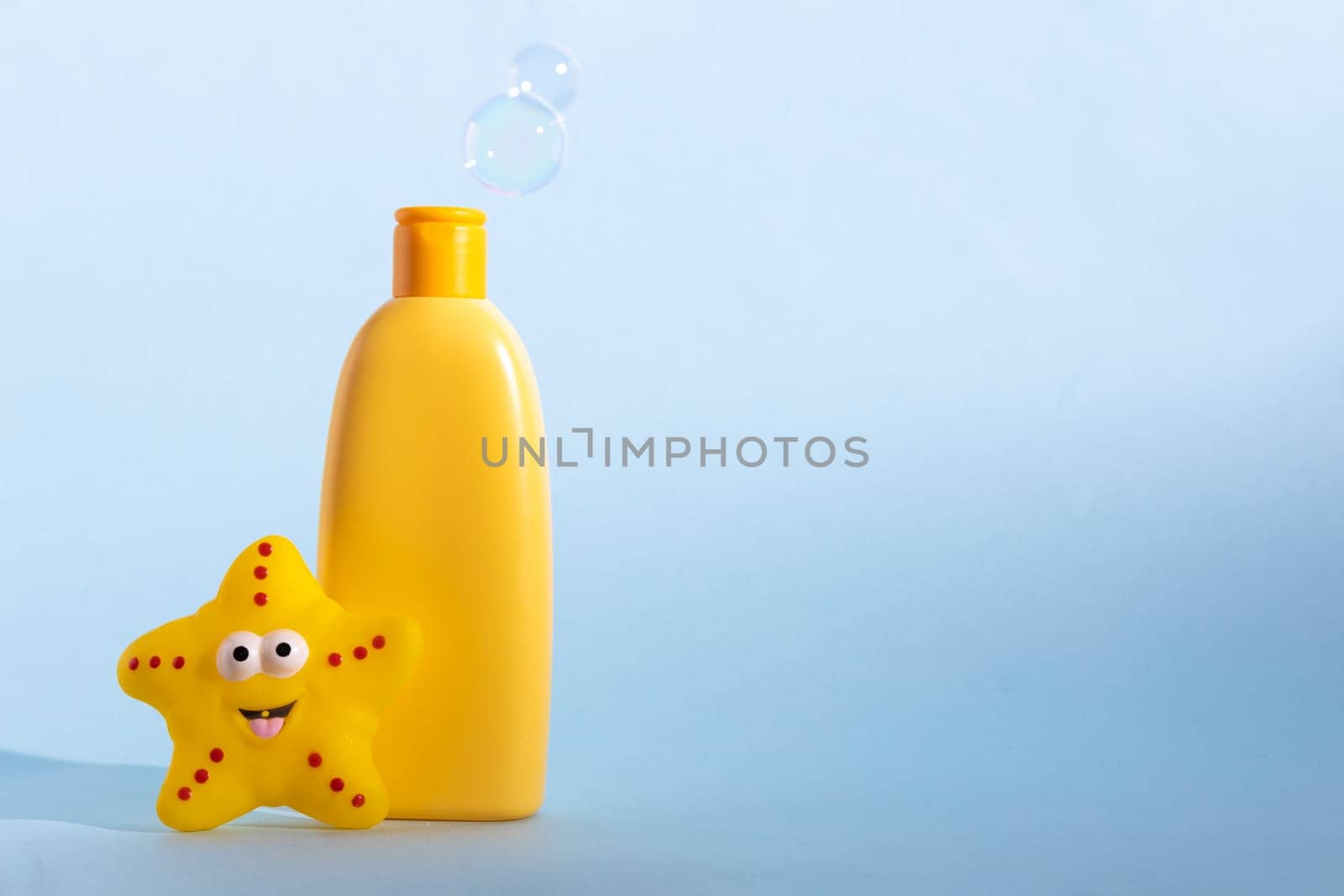 Mockup bottle of baby washing gel, bath foam, liquid soap or shampoo with yellow star fish and flying soap bubbles. Children's hygiene. Template for design. by Ri6ka