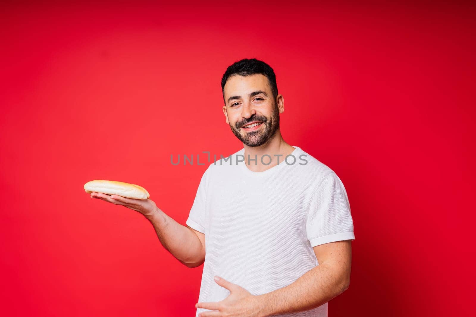 Man with freshly baked bread in hands isolated on red background studio