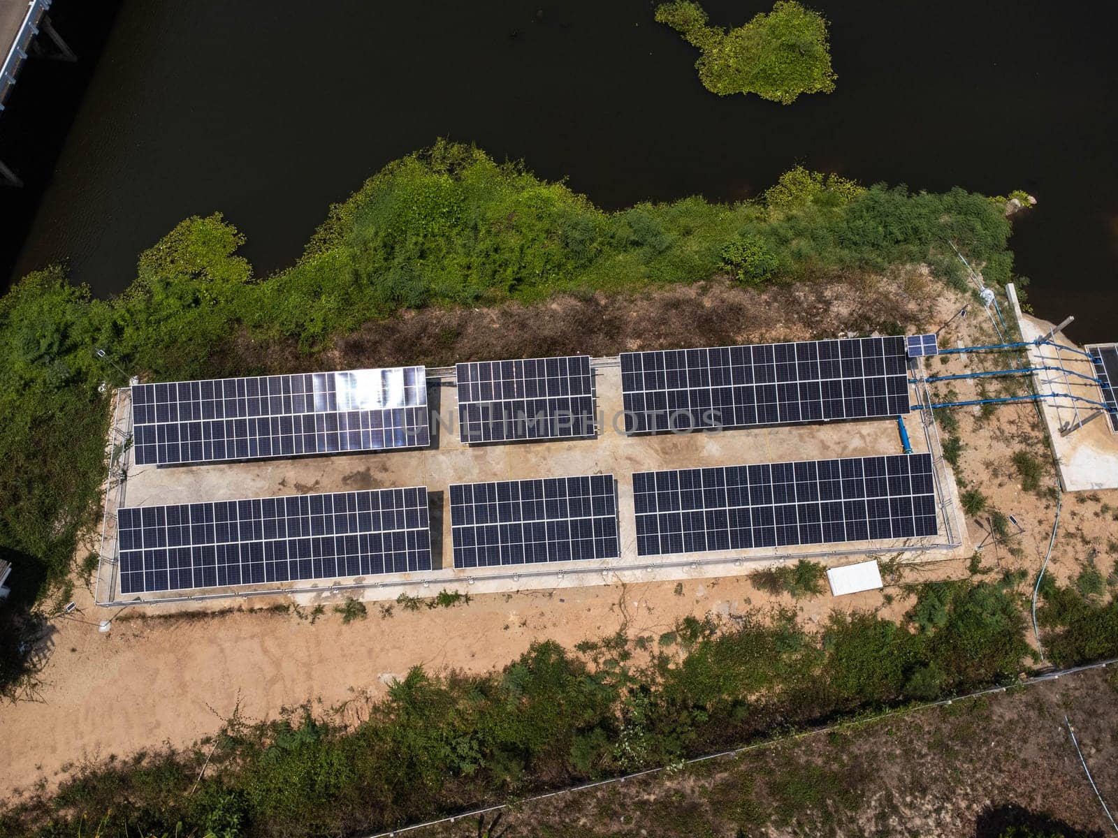 Top view on photovoltaic solar power panels. Drone aerial view of solar panels with water pumps, agricultural equipment for irrigation near rivers from clean energy or solar energy. Alternative electricity source. by TEERASAK